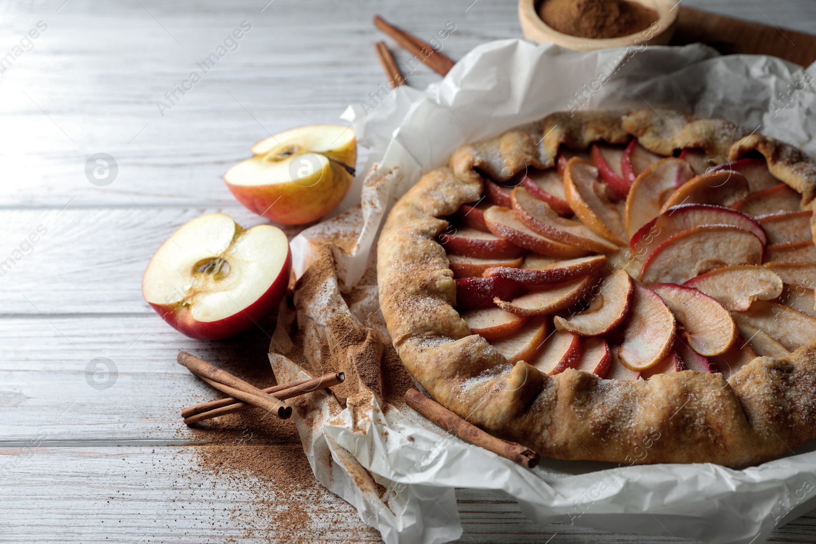 Photo of Delicious apple galette and cinnamon on wooden table