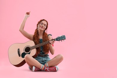 Photo of Stylish young hippie woman with guitar on pink background