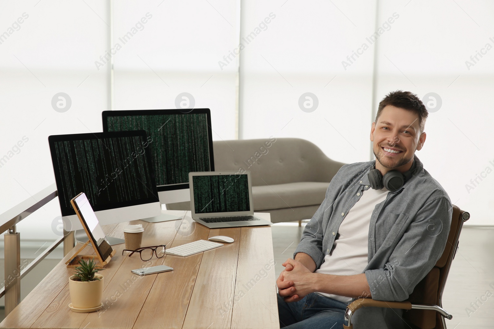 Photo of Happy programmer with headphones working at desk in office