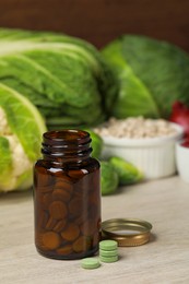 Photo of Bottle of pills and foodstuff on white wooden table. Prebiotic supplements