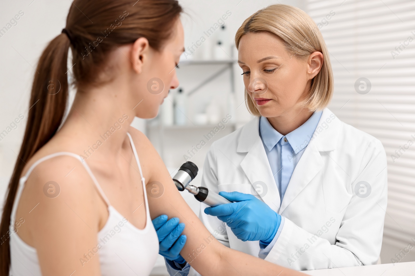 Photo of Dermatologist with dermatoscope examining patient in clinic