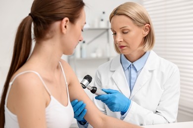 Photo of Dermatologist with dermatoscope examining patient in clinic