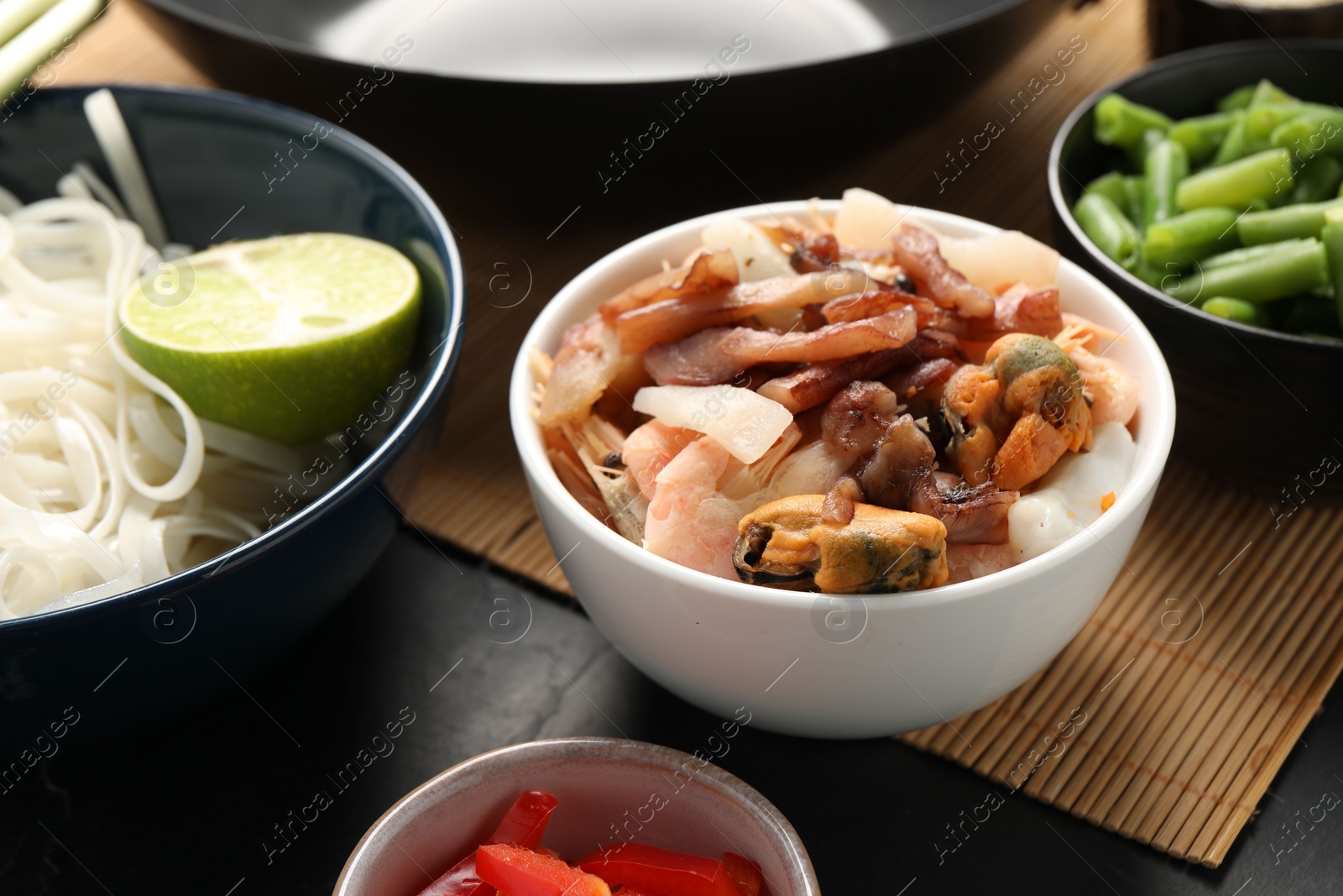 Photo of Seafood and products for cooking wok on dark table, closeup