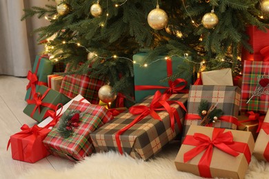 Many gift boxes under beautiful Christmas tree in room