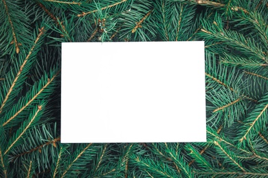 Blank card on Christmas tree branches as background, top view. Space for text