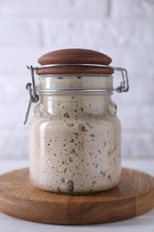 Photo of Sourdough starter in glass jar on white wooden table