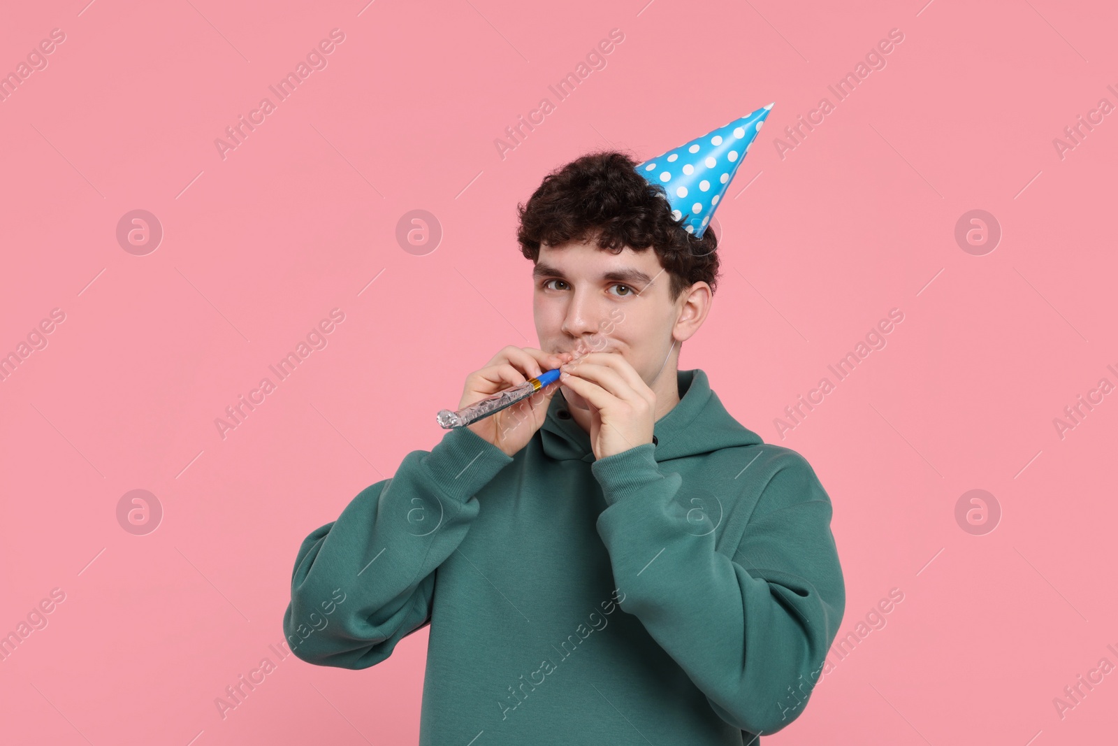 Photo of Young man in party hat with blower on pink background