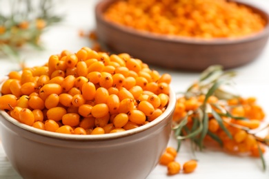 Photo of Fresh ripe sea buckthorn in bowl on white table, closeup