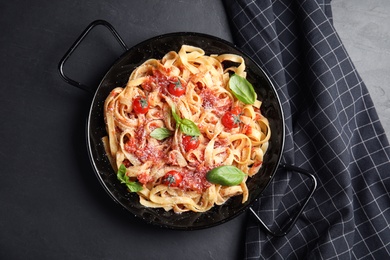 Photo of Tasty pasta and napkin on black table, flat lay