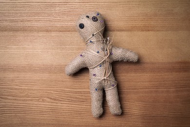 Photo of Voodoo doll pierced with pins on wooden table, top view
