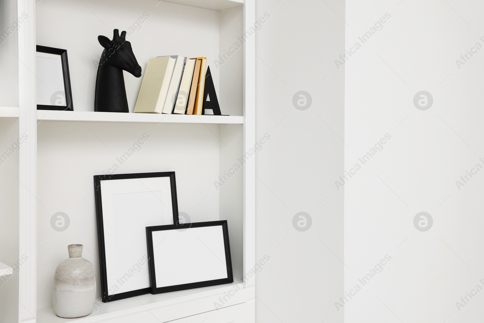 Photo of Books, frames and different decorative elements on shelving unit indoors, space for text
