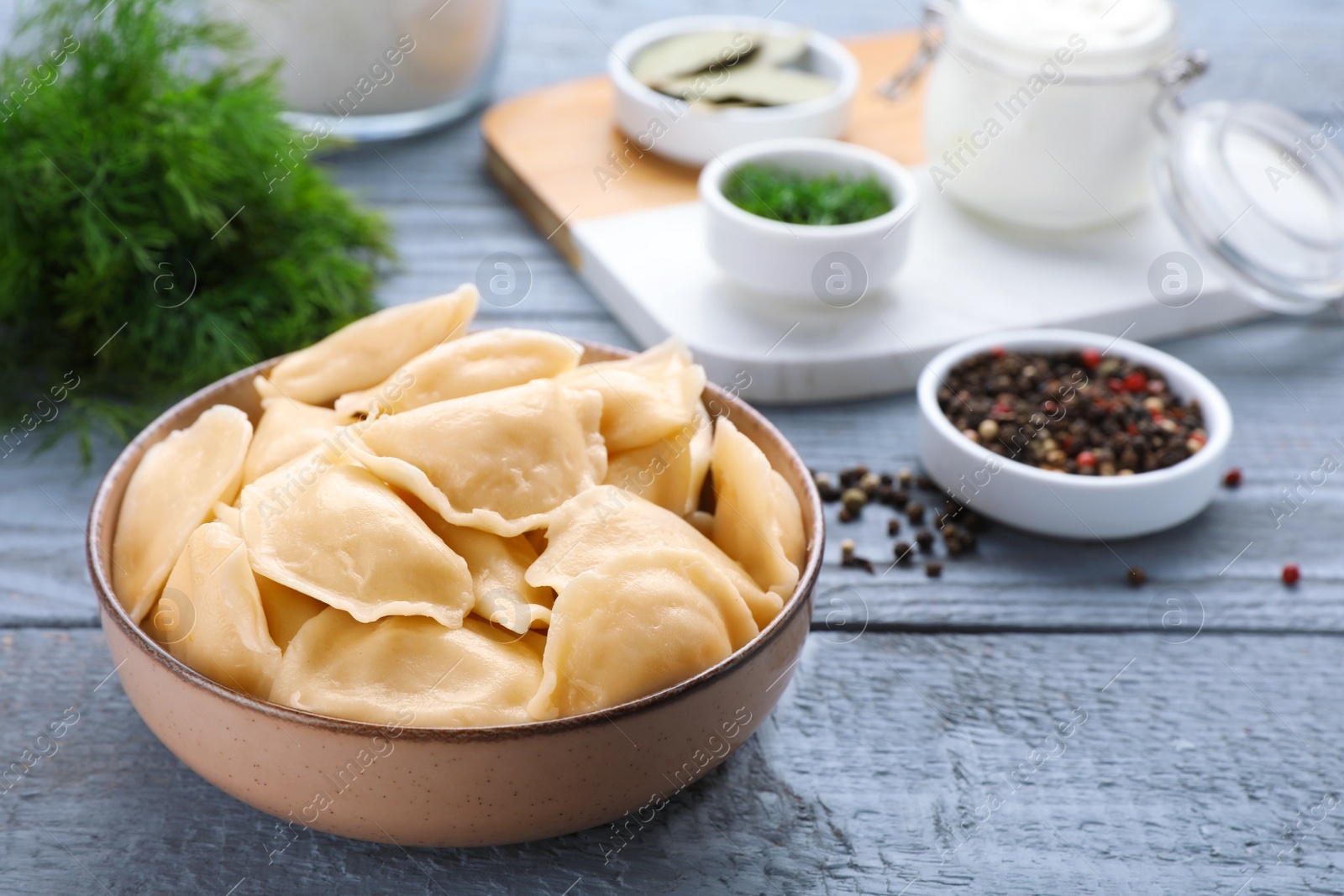 Photo of Tasty dumplings in bowl served on grey wooden table