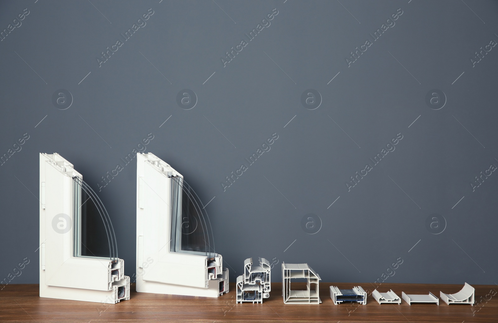Photo of Samples of modern window profiles on table against gray wall, space for text. Installation service