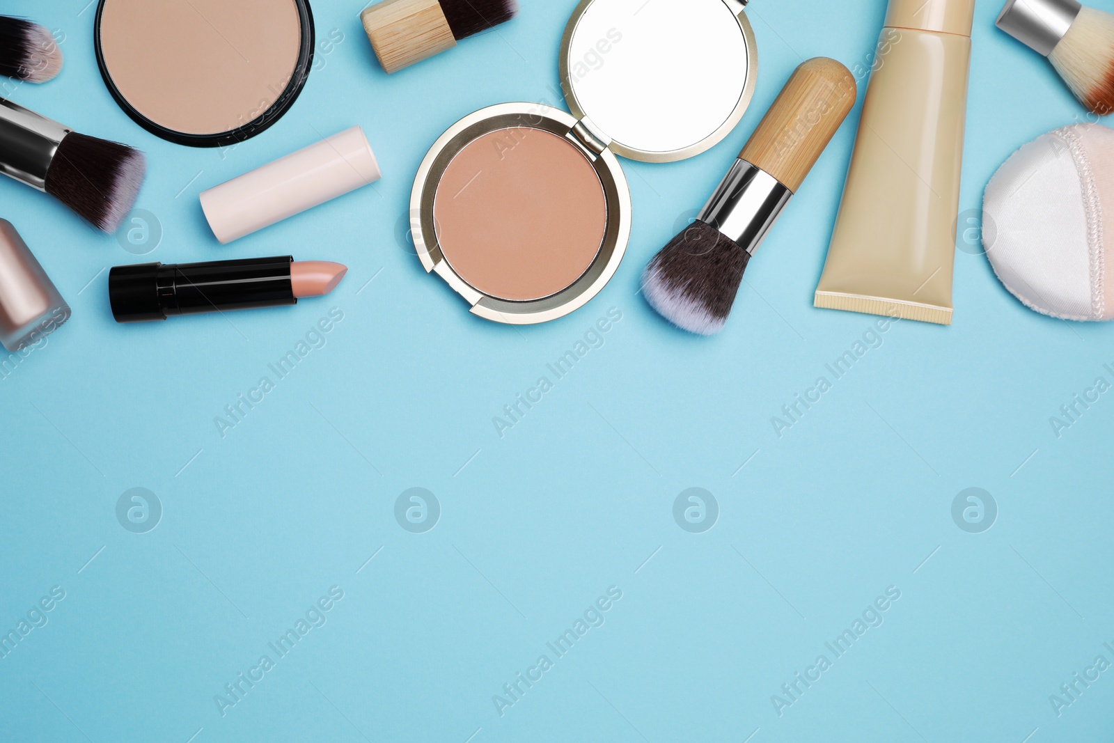 Photo of Face powders and other decorative cosmetic products on light blue background, flat lay. Space for text