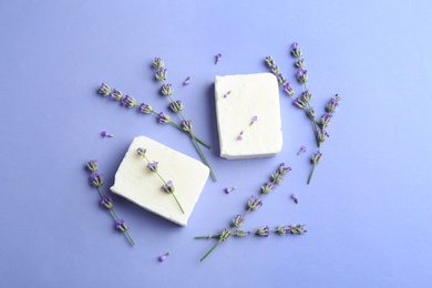 Photo of Hand made soap bars with lavender flowers on violet background, flat lay