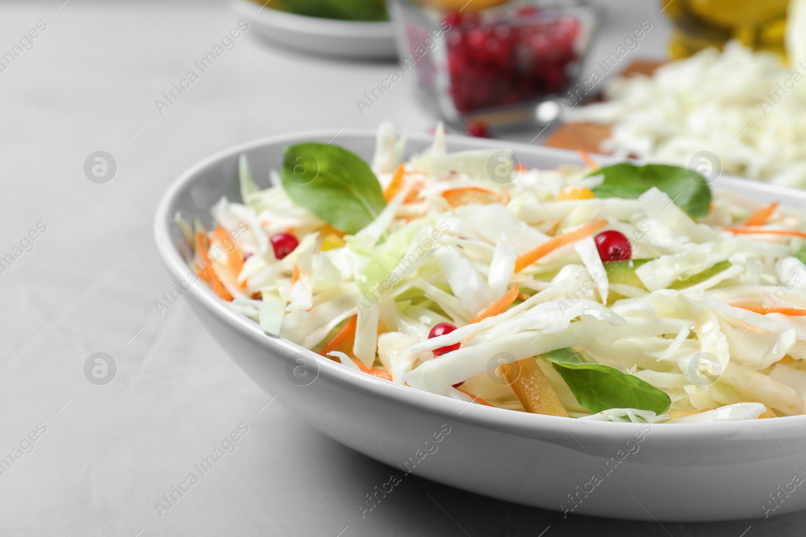 Photo of Fresh cabbage salad served on light grey table, closeup