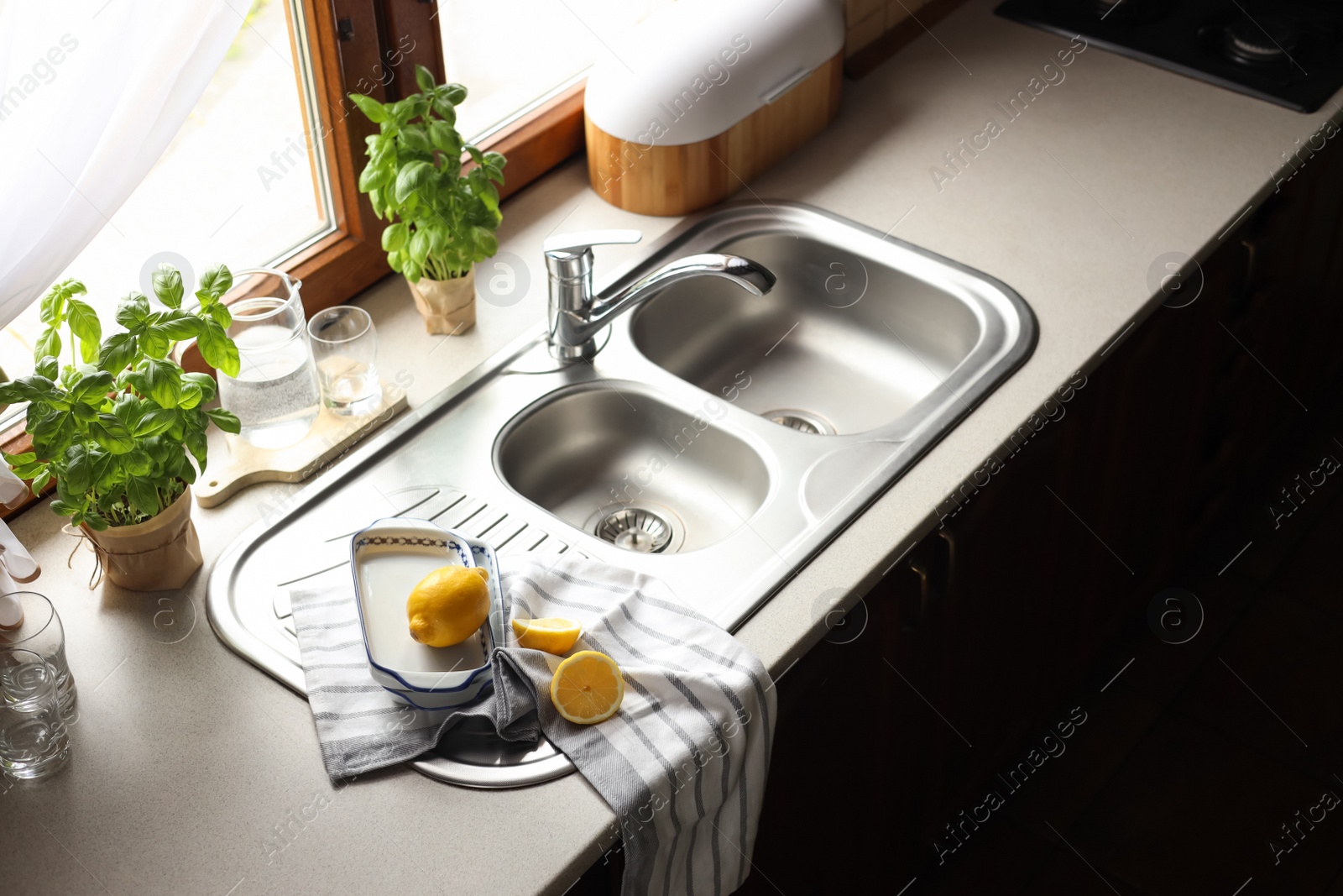 Photo of Fresh ripe lemons near sink in kitchen