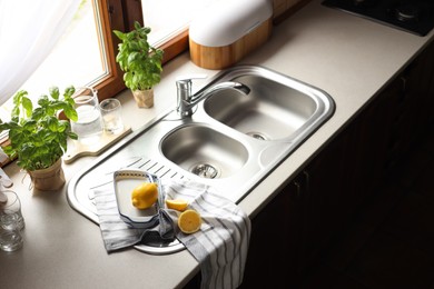 Photo of Fresh ripe lemons near sink in kitchen