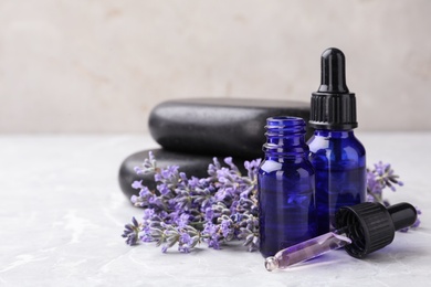 Bottles with natural lavender essential oil on table against grey background. Space for text