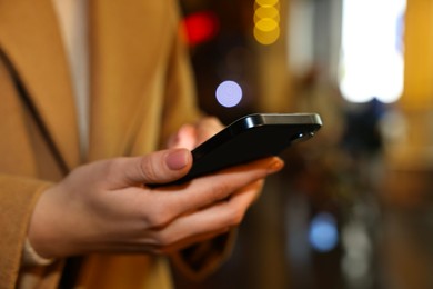 Photo of Woman with smartphone on night city street, closeup