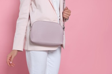 Woman with stylish bag on pink background, closeup. Space for text