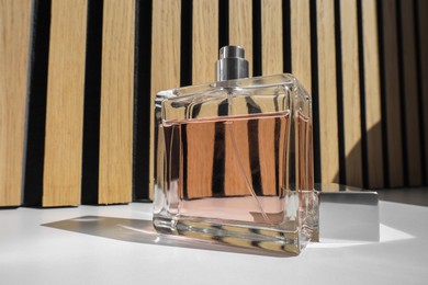 Photo of Bottle of luxury perfume on white table, closeup
