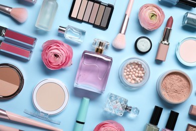 Flat lay composition with different makeup products and beautiful spring flowers on light blue background