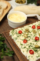 Photo of Fresh natural butter board with cut olives, dill and pepper on wooden table