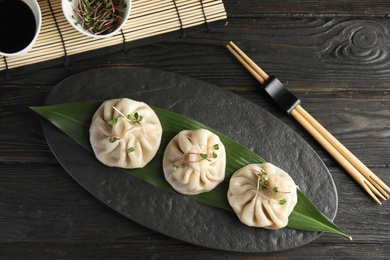 Slate plate with tasty baozi dumplings served on wooden table, top view