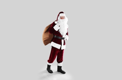Photo of Full length portrait of Santa Claus with sack on light grey background