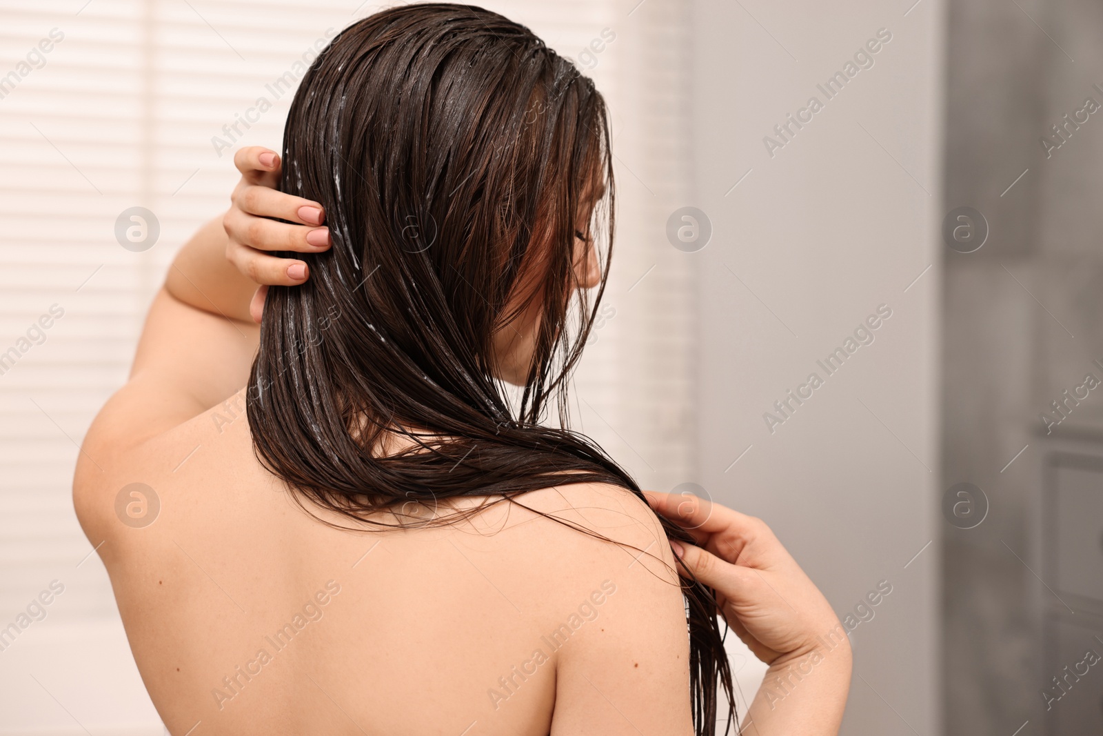 Photo of Woman applying hair mask in bathroom, back view. Space for text