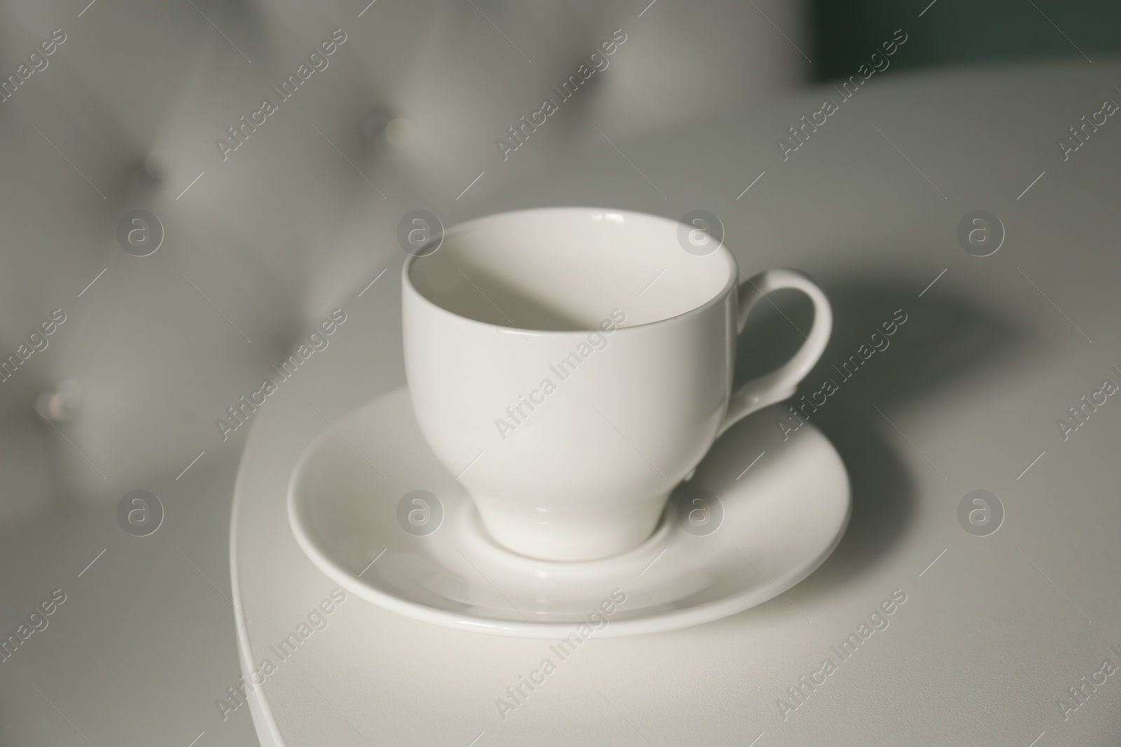 Photo of Empty cup with saucer on white table, closeup