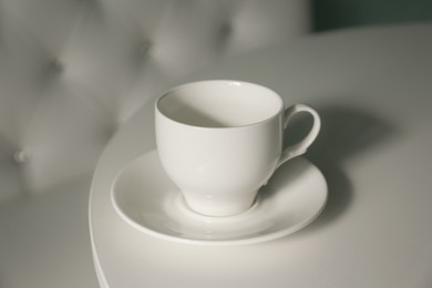 Empty cup with saucer on white table, closeup