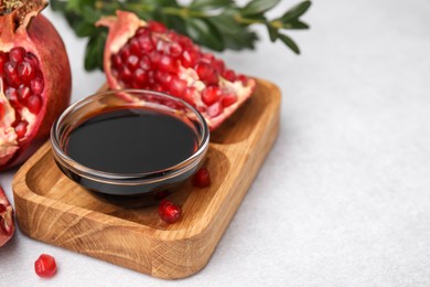 Photo of Tasty pomegranate sauce in bowl and fruits on light table, closeup. Space for text