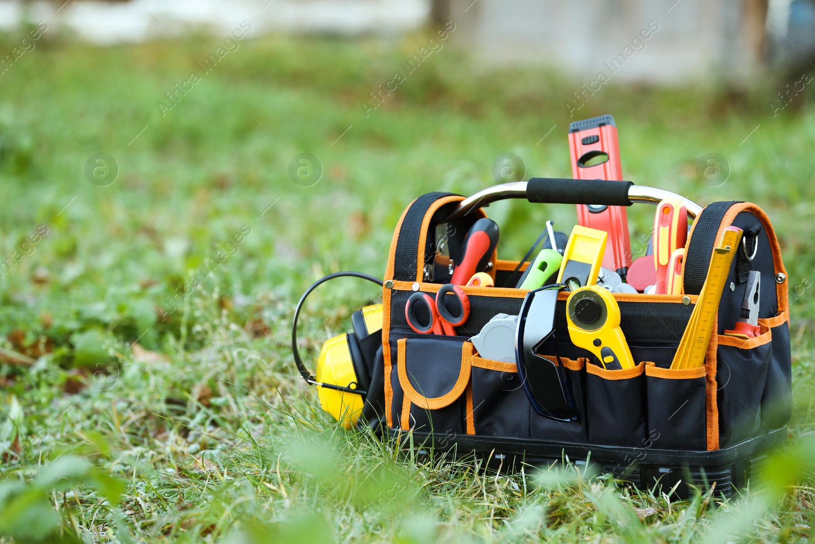 Photo of Bag with different tools for repair on grass outdoors, space for text