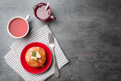 Photo of Plate with delicious pancakes and cup of tea on table