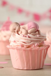 Photo of Beautifully decorated baby shower cupcake for girl with cream and topper on wooden table