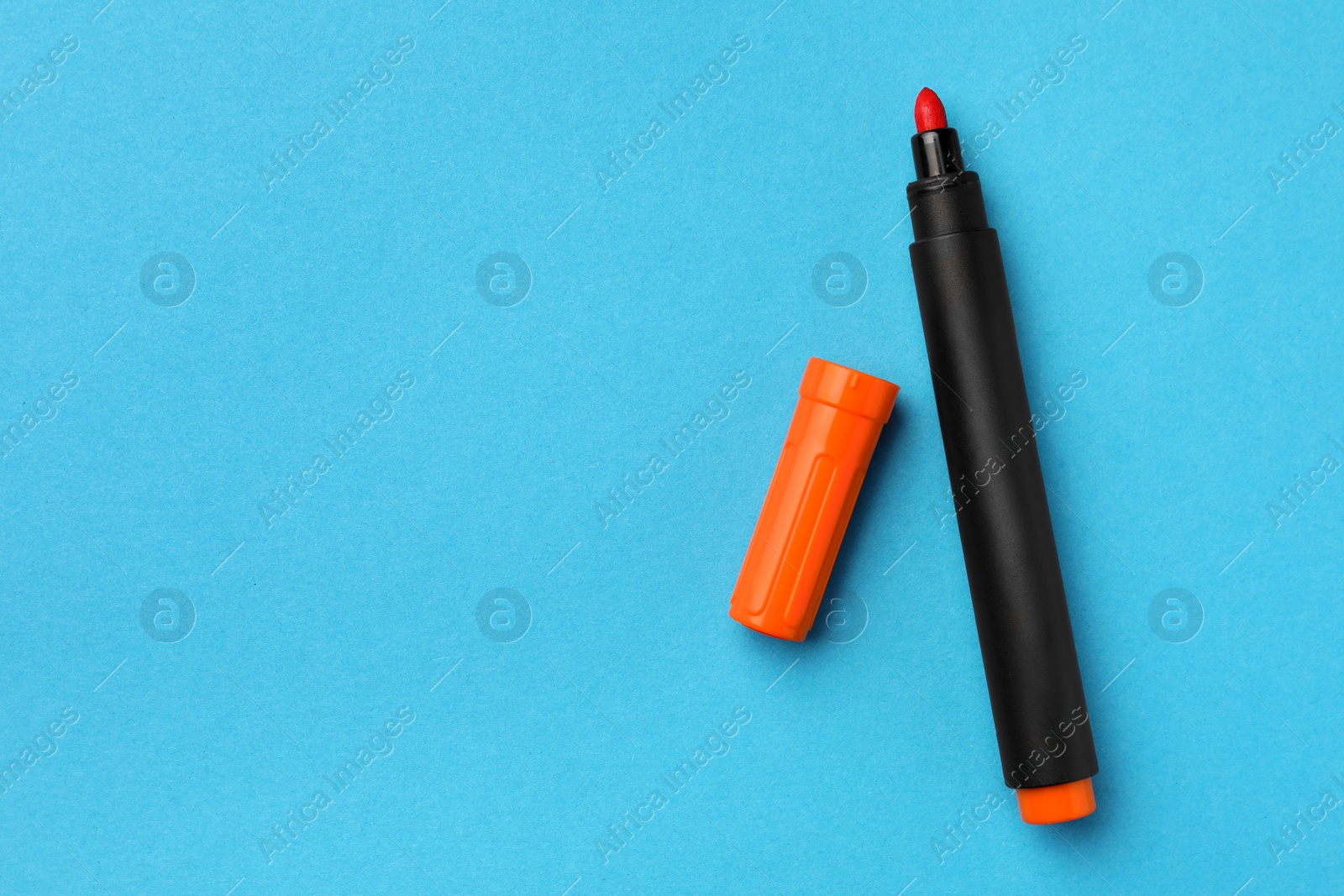Photo of Bright orange marker on light blue background, flat lay. Space for text