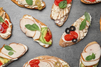 Different delicious chicken bruschettas on grey table, flat lay