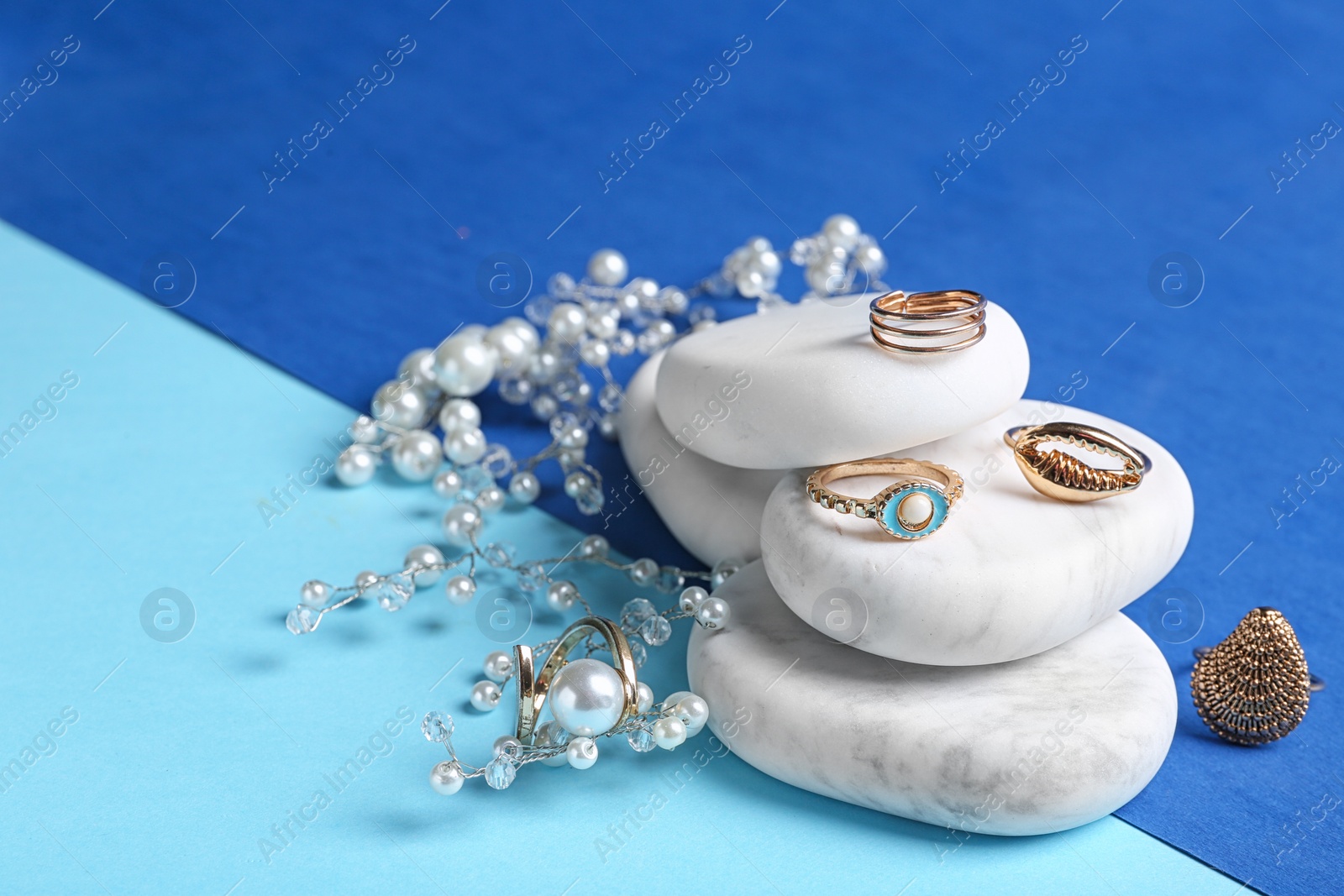 Photo of White marble stones with elegant jewelry on color background. Space for text