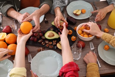 Friends eating vegetarian food at wooden table indoors, closeup