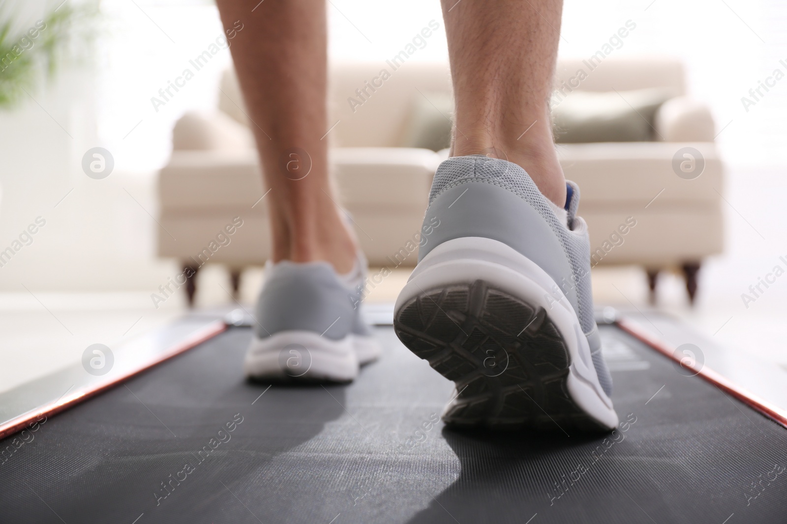 Photo of Man training on walking treadmill at home, closeup