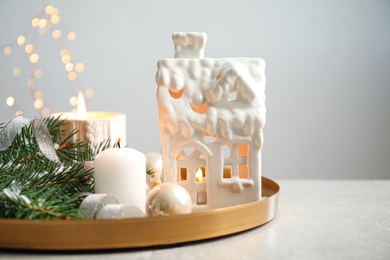 Composition with house shaped candle holder on grey table against blurred background. Christmas decoration