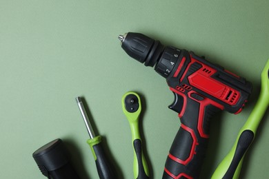 Photo of Electric screwdriver and accessories on pale green background, flat lay