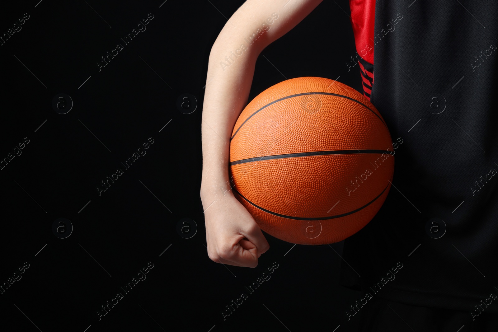 Photo of Boy with basketball ball on black background, closeup. Space for text