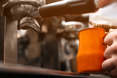 Male barista making espresso using professional coffee machine, closeup