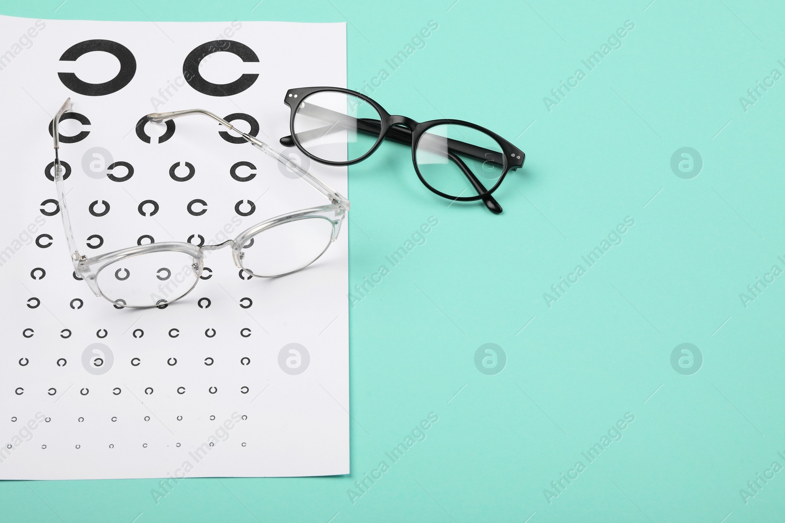 Photo of Vision test chart and glasses on turquoise background, space for text