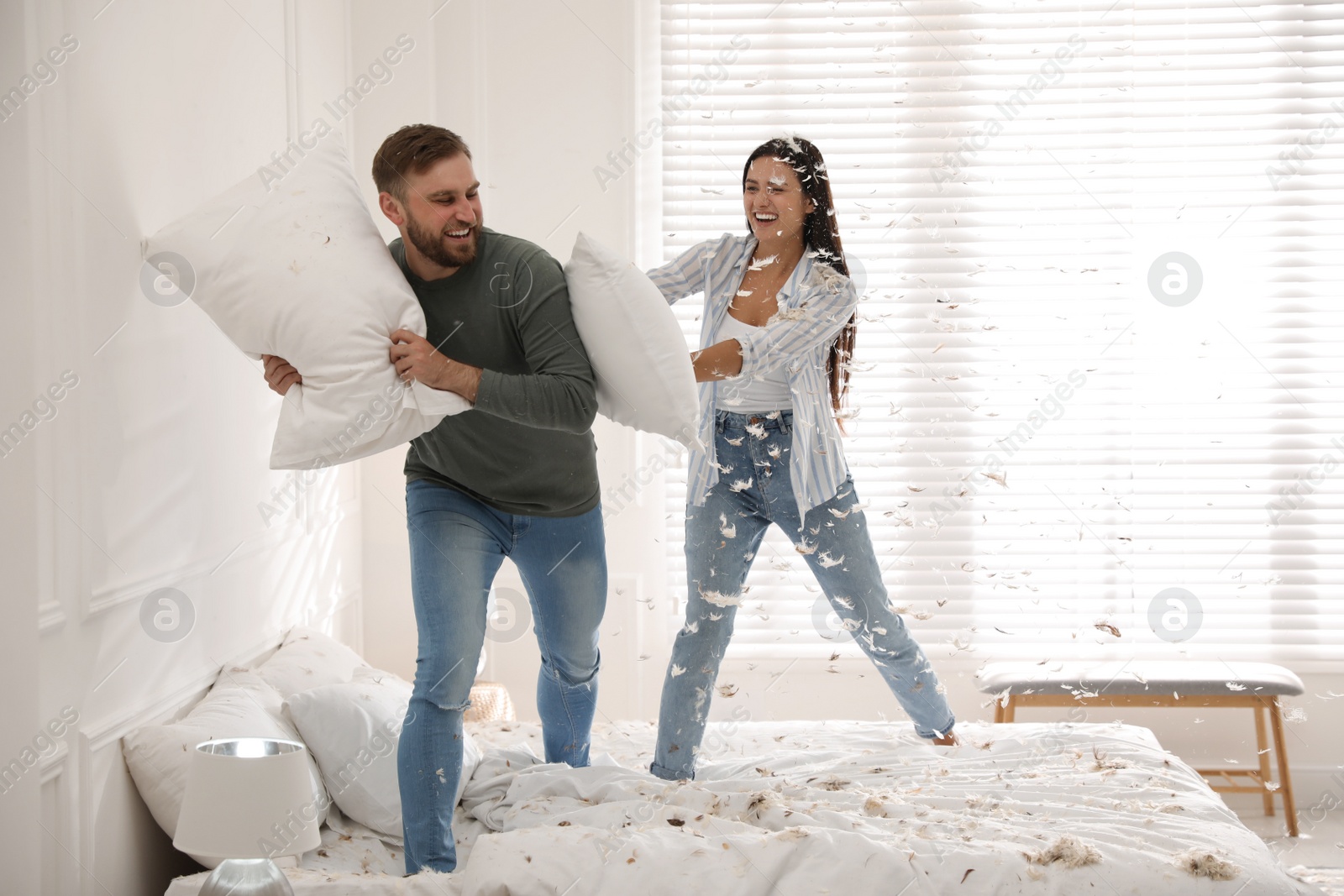 Photo of Happy young couple having fun pillow fight in bedroom