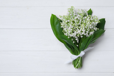 Beautiful lily of the valley flowers on white wooden table, top view. Space for text