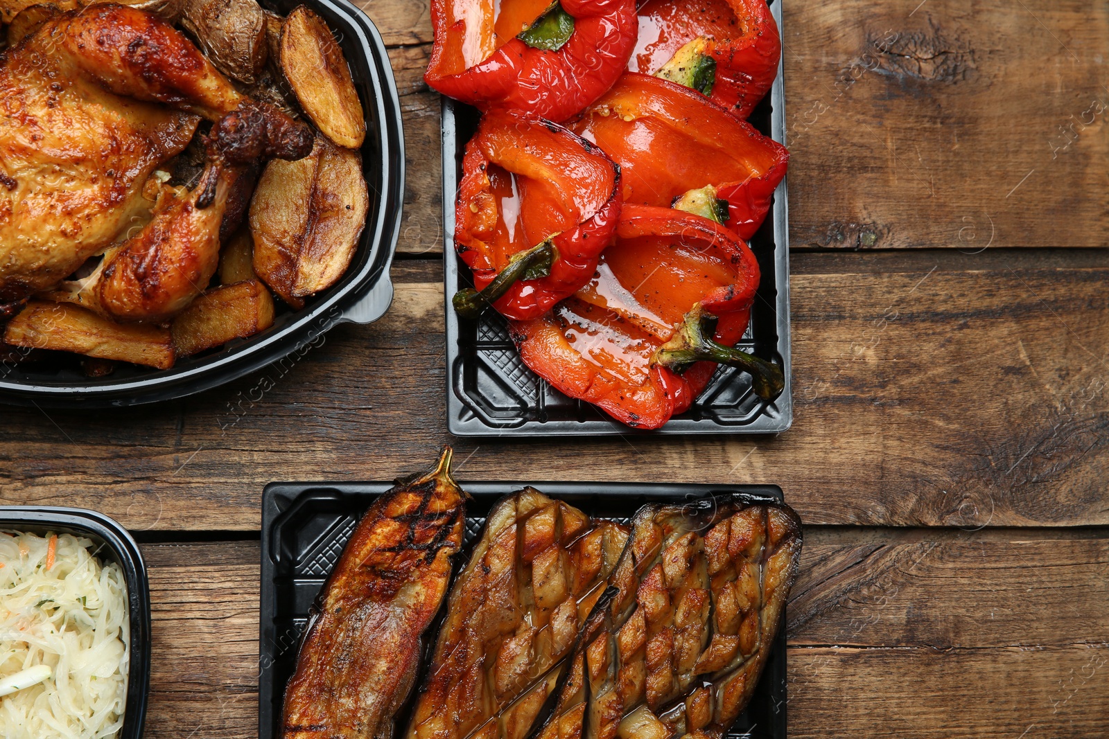 Photo of Plastic containers with different dishes on wooden table, flat lay. Food delivery service